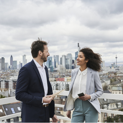 Male and female partners discussing while standing on rooftop